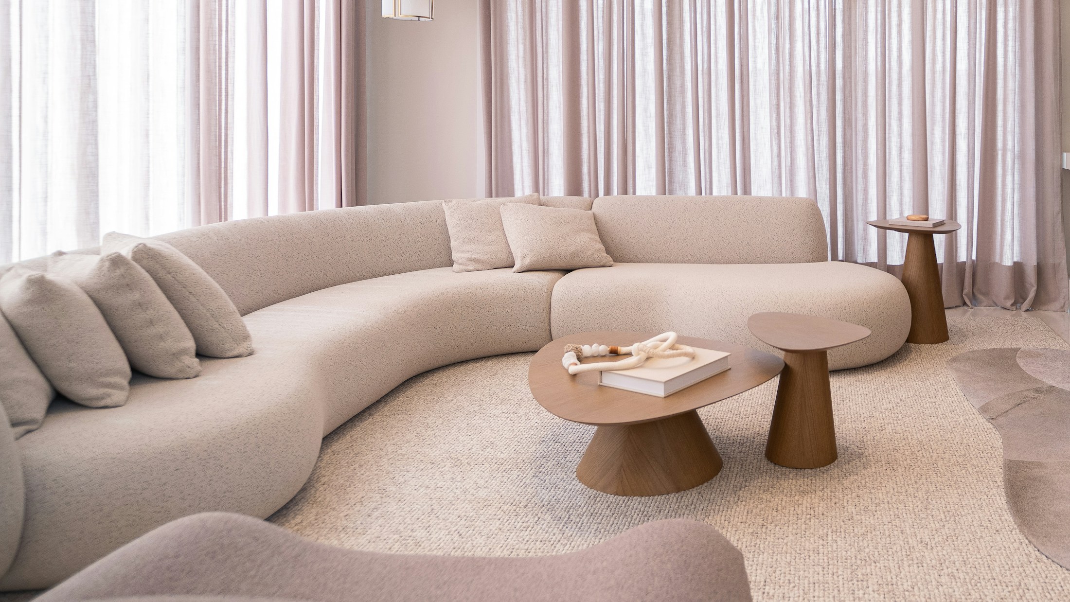 Sillón curvo de bouclé color crema en un living cálido con luz natural